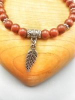 A bracelet with leaf and silver charm.
Product Name: A RED JASPER BRACELET WITH FEATHER with leaf and silver charm.