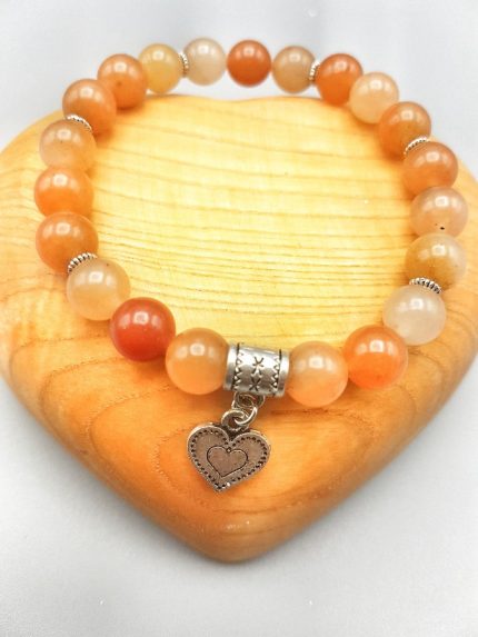 UN BRACCIALE DI AVVENTURINA ROSSA CON CUORE con una pietra arancione e un ciondolo a forma di cuore.