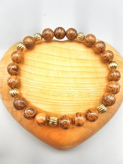 A wooden heart with a BRONZETE BRACELET WITH GOLDEN BALLS on it.