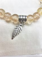 A bracelet with Leaf and silver charm.