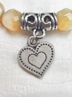 Un braccialetto con un pendente a forma di cuore e perle di agata gialla.