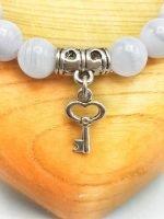 A bracelet with a silver key and a white stone.