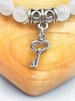 A white moonstone bracelet with key pendant.
