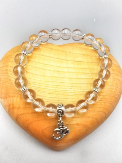 An 8MM ROCK CRYSTAL BRACELET WITH OM PENDANT with silver charm and clear quartz beads.