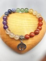 A BRACELET OF THE SEVEN CHAKRAS WITH PENDANT with a tree of life pendant on top.