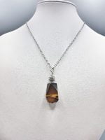 A STONE TIGER'S EYE PENDANT with silver chain.