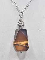 A STONE TIGER'S EYE PENDANT on a silver chain.