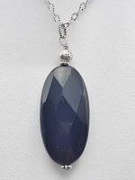 AN OVAL BLACK ONYX PENDANT with blue oval stone on a silver chain.