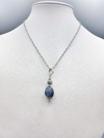 A SODALITE PENDANT hanging from a silver necklace.