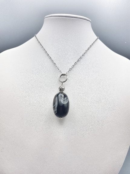 AN OVAL BOTSWANA AGATE PENDANT on a silver chain.