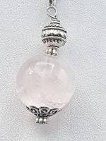 A pendant with a rose quartz sphere on it.