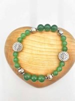 A MIXED GREEN AVENTURINE BRACELET on a wooden base.