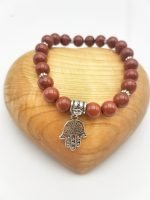A RED JASPER BRACELET with a silver pendant in the shape of the hand of Fatima.