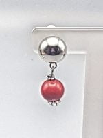 Description: A red coral bead hangs from a clip-on earring with coral.