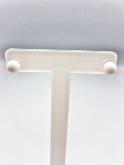 A close-up of a white plastic shelf showing the WHITE AGATE EARRINGS.