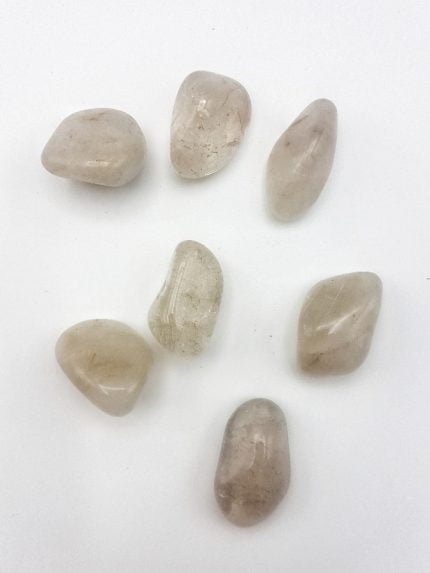 A cluster of tumbled RUTILATED QUARTZ STONES on a white surface.