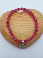 A ruby jade bracelet with a silver heart-shaped charm.