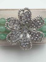A green aventurine bracelet with a flower and rhinestone accents GREEN AVENTURINE BRACELET AND FLOWER WITH RHINESTONES.