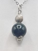 A SPHERICAL MUSKY AGATE PENDANT necklace with a black stone on top.