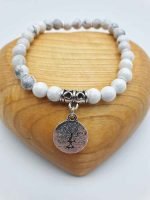 A white HOWLITE AND TREE OF LIFE BRACELET, with a charm in the shape of a tree of life, made of howlite.