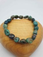 A bracelet with turquoise pearls on top of a wooden heart.
(Chrysocolla) CHRYSOCOLLA BRACELET