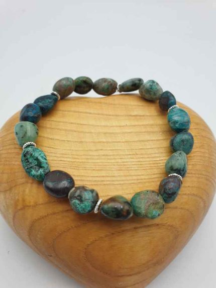 A bracelet with turquoise pearls on top of a wooden heart.
(Chrysocolla) CHRYSOCOLLA BRACELET