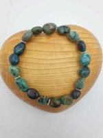 A chrysocolla bracelet with green and blue stones on a wooden heart.