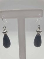 The BLACK ONYX EARRINGS LARGE DROP are displayed on a stand.