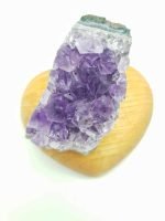 An 8 CM AMETHYST DRUSA FOR PURIFICATION placed on a wooden heart.