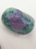 Two stones TUMBLED RUBY ZOISITE on a white surface.