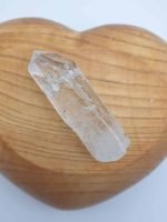 Punte in cristallo di rocca per armonizzare aura e chakra, posato su un cuore di legno.