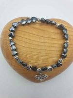 A black and silver HEMATITE HEART-SHAPED BRACELET THAT GIVES STRENGTH AND VITALITY TO INCREASE THE WILL TO LIVE with heart charm that gives strength and vitality to increase the will to live.