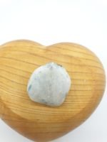 A small TUMBLED WHITE MOONSTONE resting on a heart-shaped wooden box.