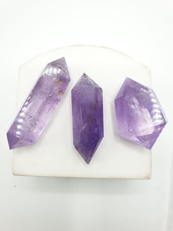 Three crystals BITERMINATED AMETHYST TIPS on a white surface.