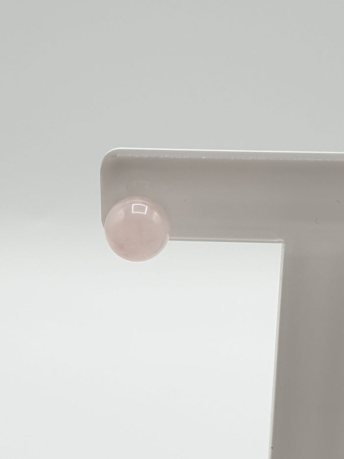 An earring with a ROSE QUARTZ EARRINGS 8 MM IN SILVER on top of a white object.