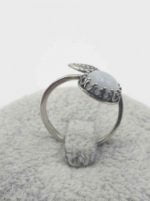 A RING WITH A WHITE CAT'S EYE AND SILVER LEAF.
