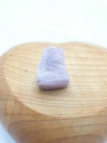 A tiny raw KUNZITE rests on a wooden heart.