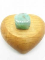 A TUMBLED CHRYSOPRASE stone in a heart-shaped wooden box.