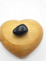 A black onyx stone sits on top of a wooden heart, with TUMBLED BLACK ONYX.