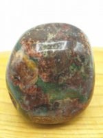 A TUMBLED LEOPARD JASPER bead on a wooden surface.