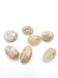 Group of oval-shaped stones on a white background, adorned with SAKURA AGATE TUMBLED CHERRY BLOSSOMS.