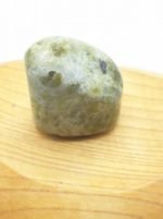 Una pietra verde VESUVIANITE O VASONITE BURATTATA appoggiata su un tagliere di legno.