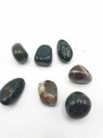 Un gruppo di pietre ELIOTROPIO BURATTATO nere e marroni su una superficie bianca ELIOTROPIO BURATTATO.