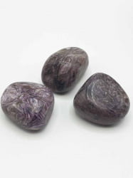 Three CHAROITE stones TUMBLED on a white surface.