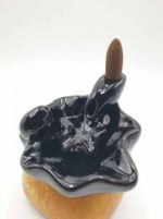 Una FONTANELLA CASCATA DI FUMO SHANTI in ceramica nera posata su una base di legno, che evoca un senso di tranquillità Shanti.