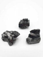 Tre pezzi di roccia nera su sfondo bianco, con Pietra Pepite Shungite Elite Grezza.