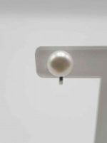 Clip-on earrings with pearls on a white table.