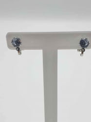 Un paio di orecchini Orecchini a Clip con Zircone su un supporto bianco decorato con zirconi a clip.