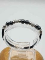 A MEN'S BRACELET WITH HEMATITE, WHITE HOWLITE AND BLACK LEATHER CORD with silver beads.