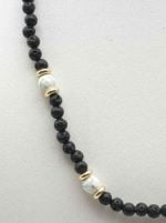 A MEN'S NECKLACE WITH LAVA STONE AND HOWLITE with black lava pearls and howlite pearls.